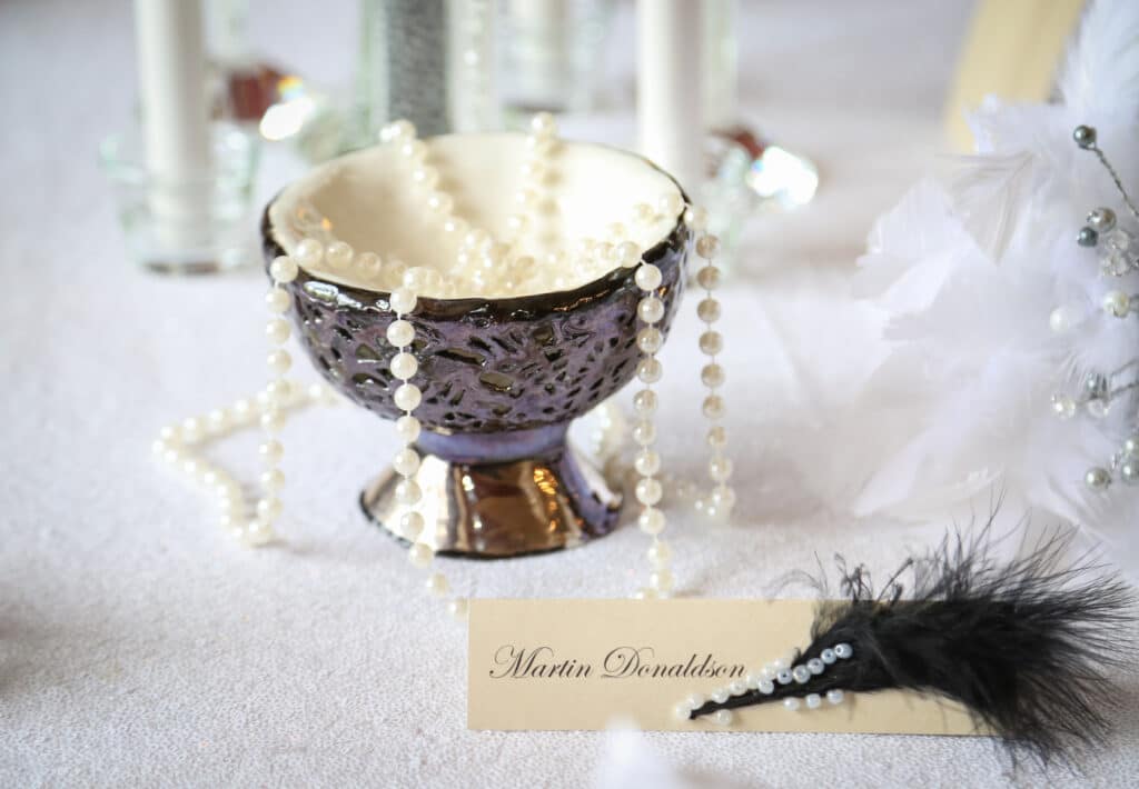 Venue styling services - 30s themed venue styling featuring pearls feathers, a monochrome, and an original artwork in the porcelain bowl by sculpture and ceramic artist Liz Watts MUA