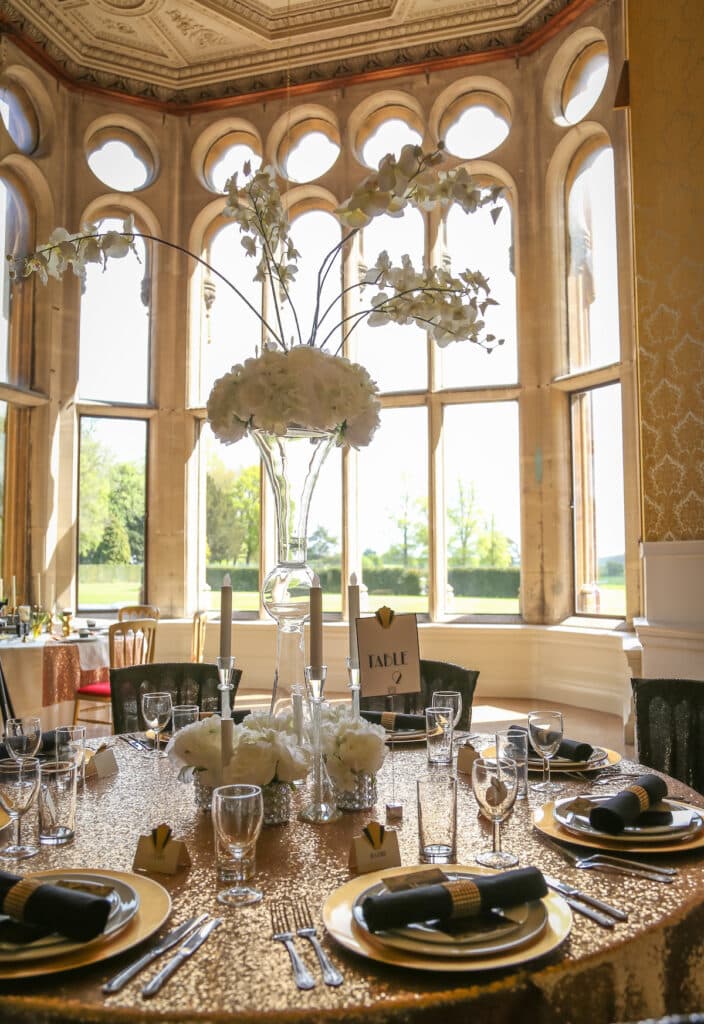 Orchids and hydrangeas in tall vase for a 20s themed centrepiece