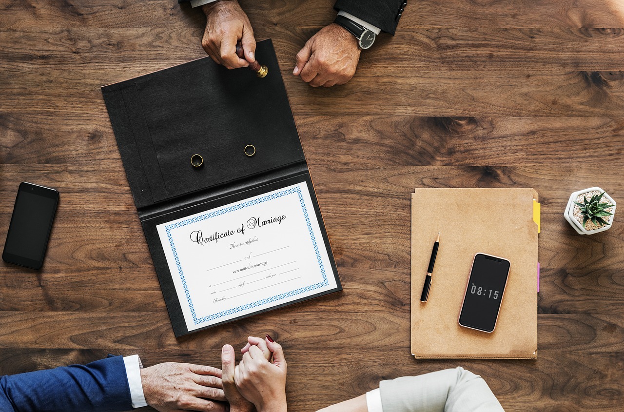 marriage certificate on a desk and people's hands