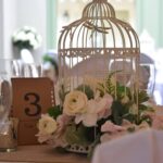 Centrepiece of a birdcage filled with flowers perfect for a rustic themed venue decor