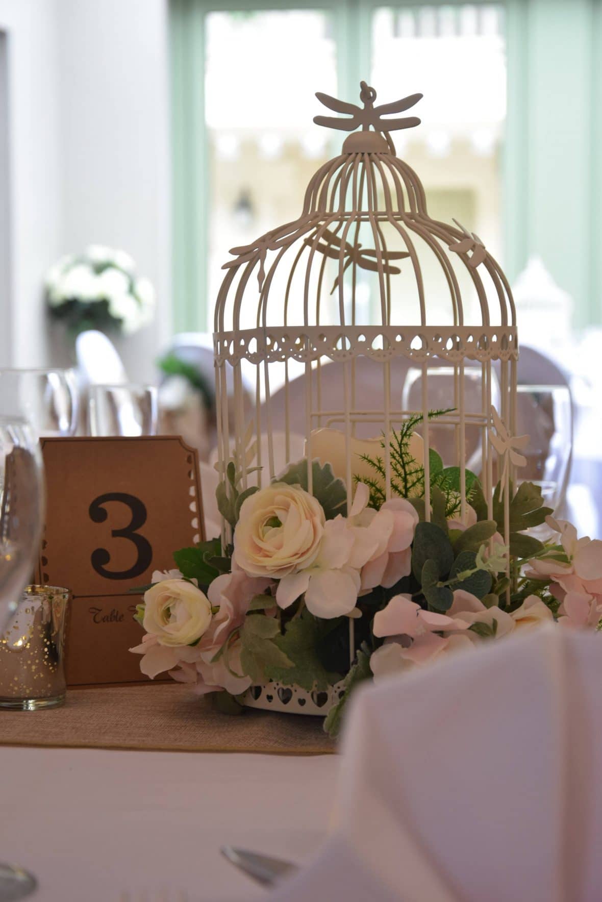 Centrepiece of a birdcage filled with flowers perfect for a rustic themed venue decor