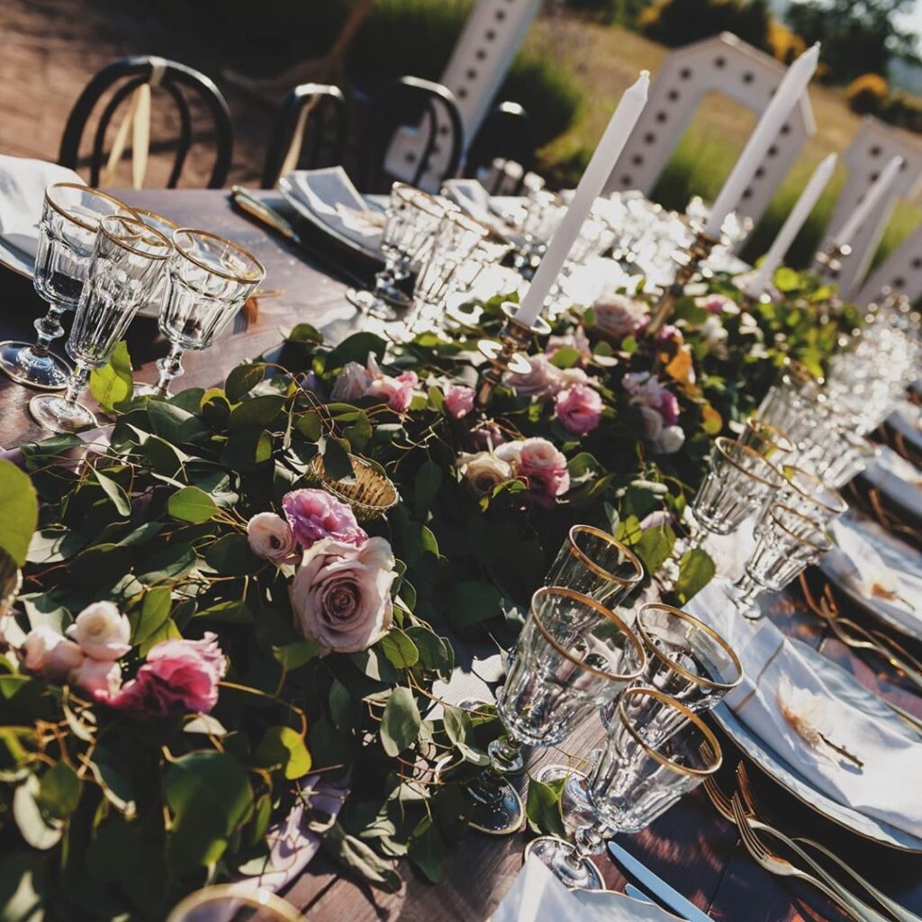 An Intimate Italian Wedding Day - flowers down centre of a table setting with glassware, cutlery and candles.