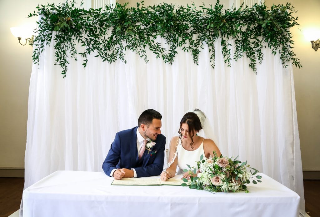 Couple sat in front of backdrop at their wedding