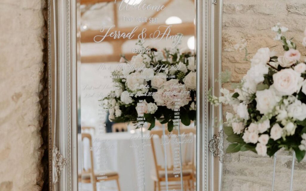 Amy and Jerrad at Kingscote Barn chose a personalised mirror for their table plan. Created by Sandra of Fabulous Functions UK it was themed with floating tealights in cylinder vases and a glorious floral arrangement