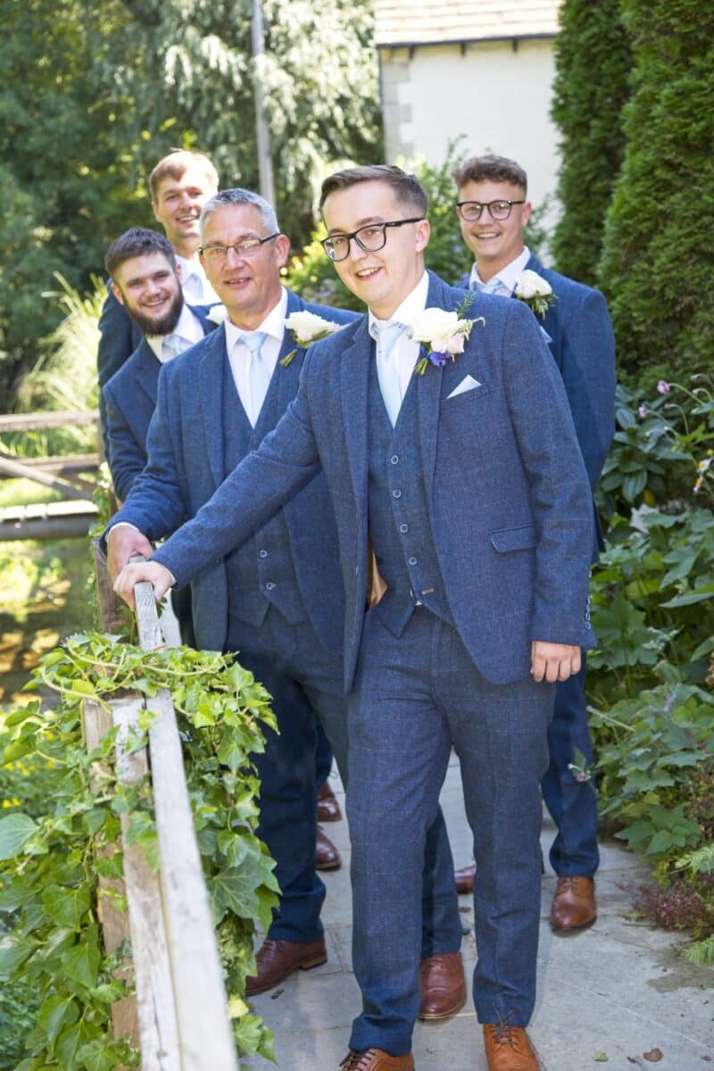 A summer wedding on the hottest day of the year. Groom Surrounded by his groomsmen on their blue suits and creamy colour palette buttonholes.